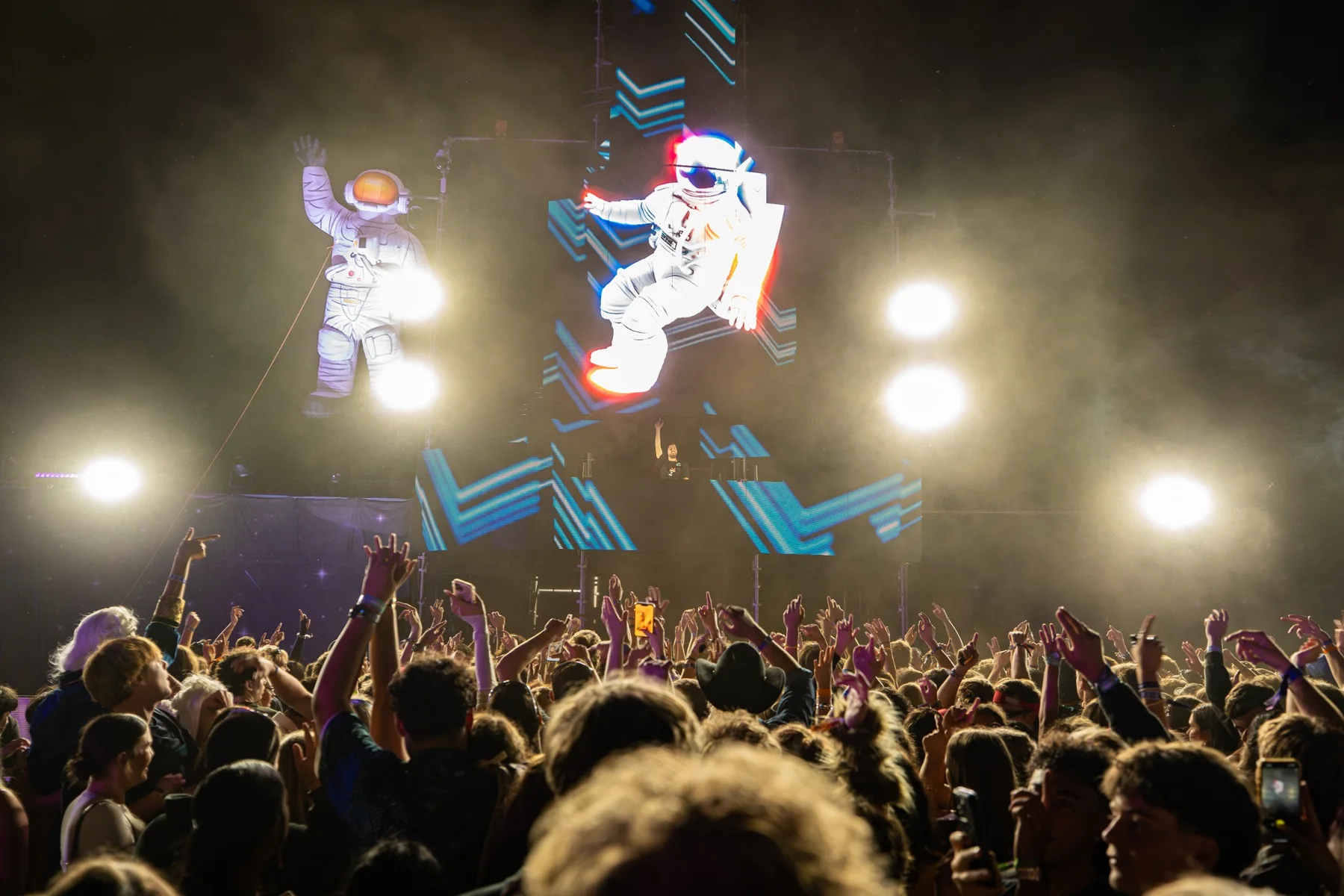 Large festival crowd facing a brightly lit stage